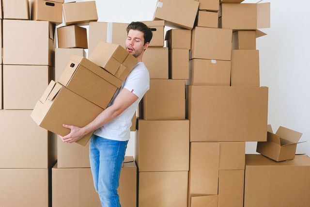 Worker carrying a stack of moving boxes during a cleanout