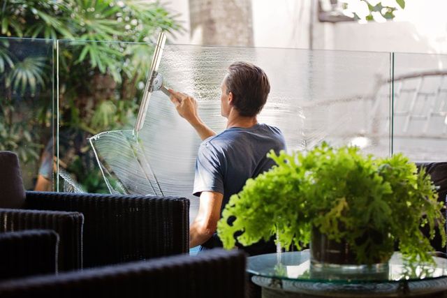 Worker cleaning a glass panel with a squeegee
